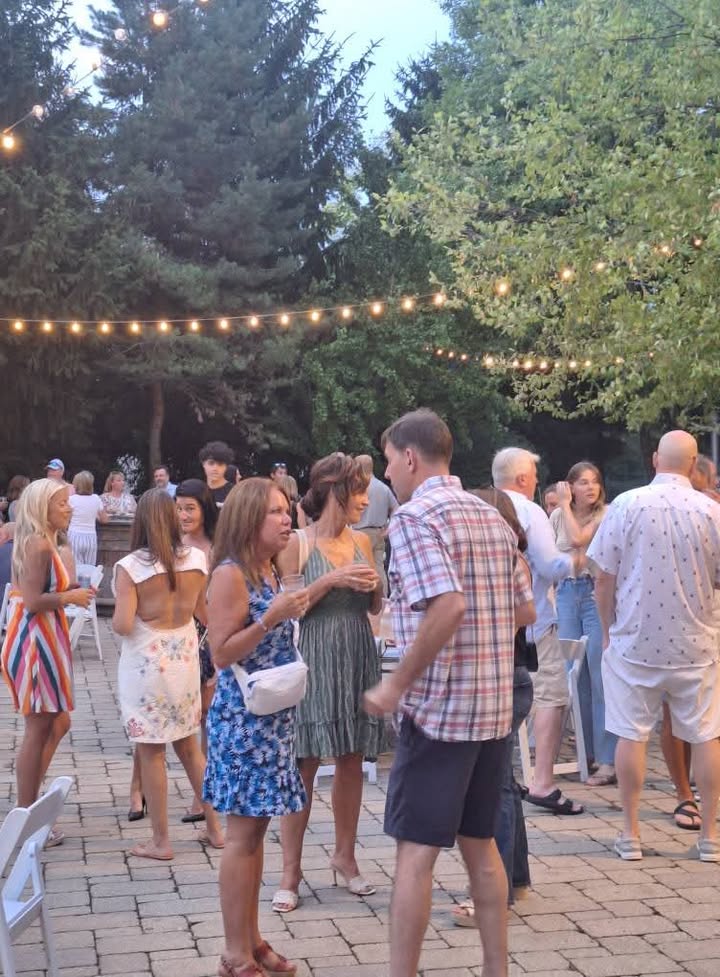 Crowd mingling under string lights at outdoor event