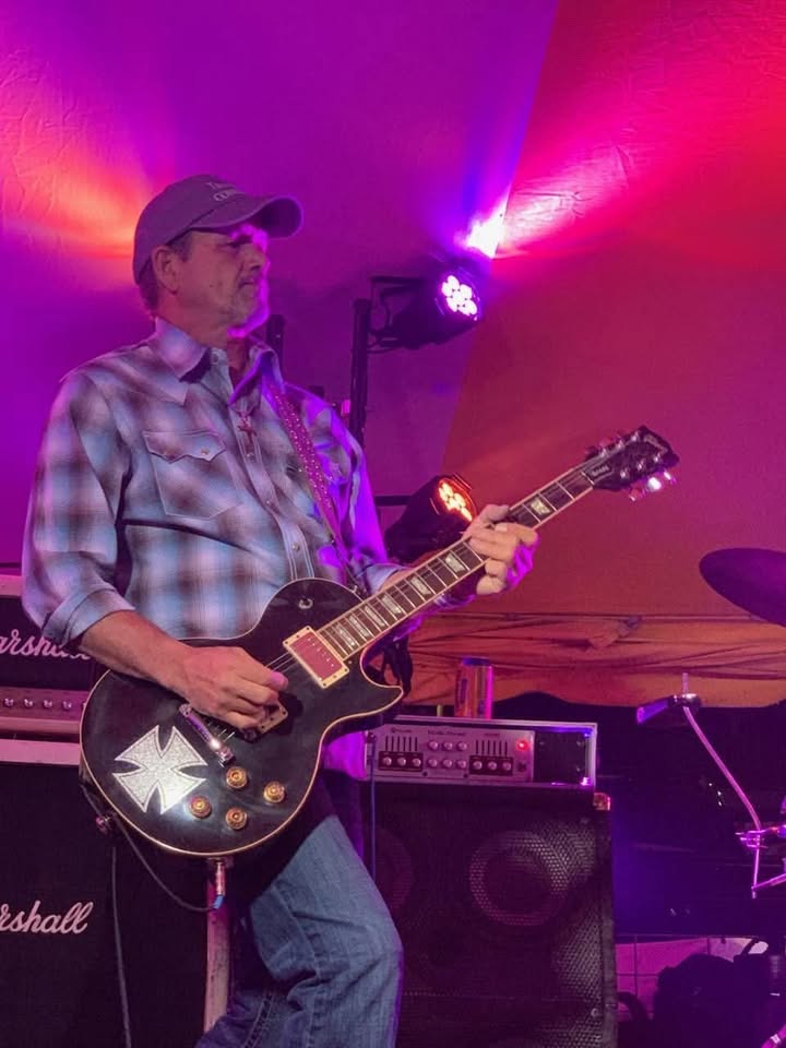 Guitarist playing electric Les Paul under stage lights